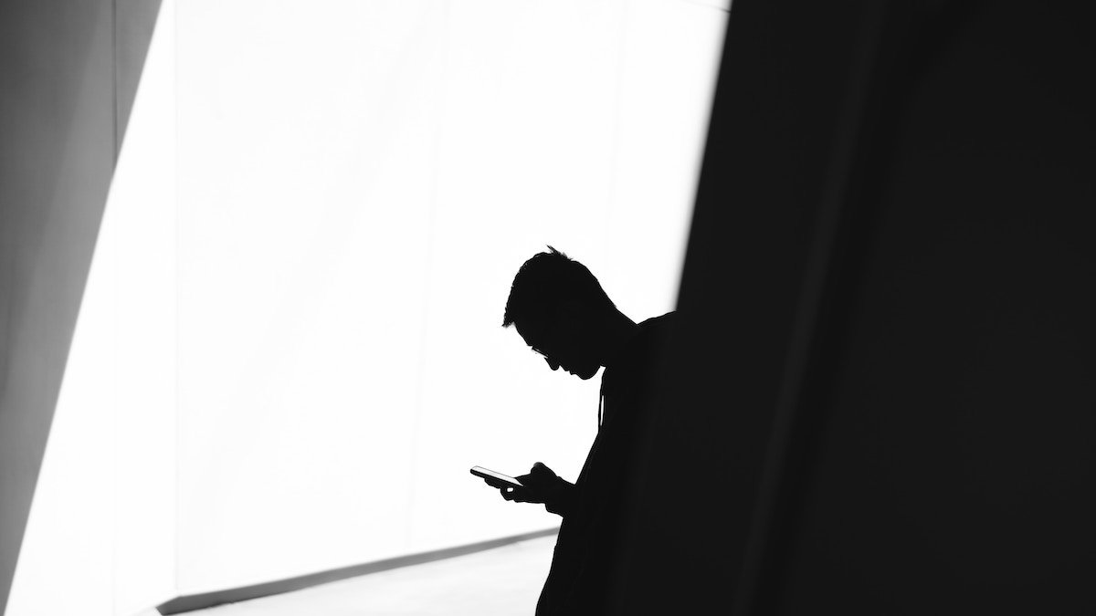 Man looking at phone in shadow