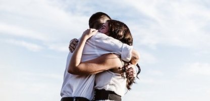 Husband and wife embracing in a hug with skyline