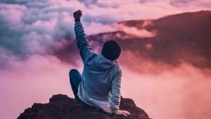 Man Raising Hand in Celebration on Mountain